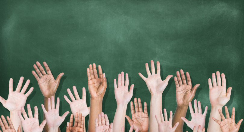raised hands in front of blackboard