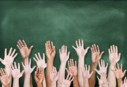 raised hands in front of blackboard